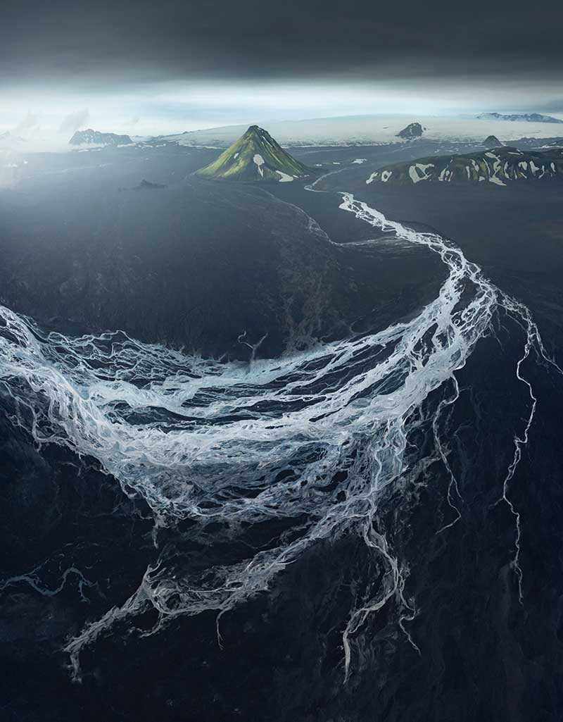 Maelifell in Iceland as seen from drone perspective. The glacier runs a network of lines weaving together and leading to a mountain in the distance.