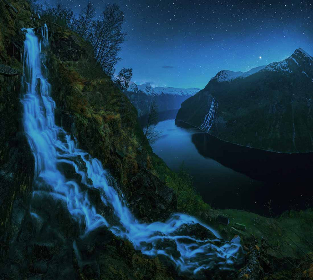 Night photo of the seven sisters waterfall in Norway as seen from another waterfall across the fjord.