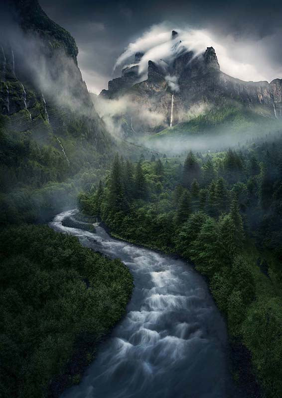 Sixt-Fer-a-Cheval a stream flows through a misty forest to a misty mountain with waterfalls running down the sides.