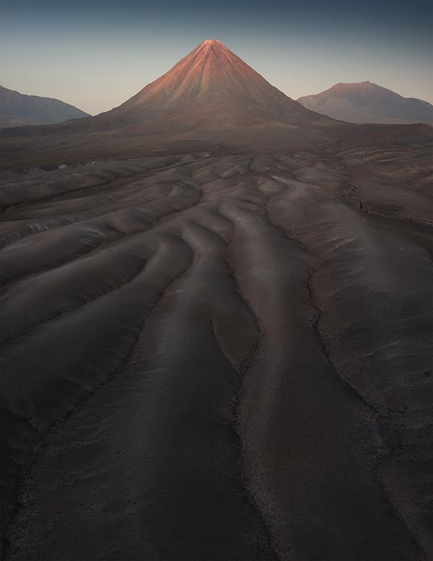 lines in the sand dunes lead toward a volcano in the Atacama desert.