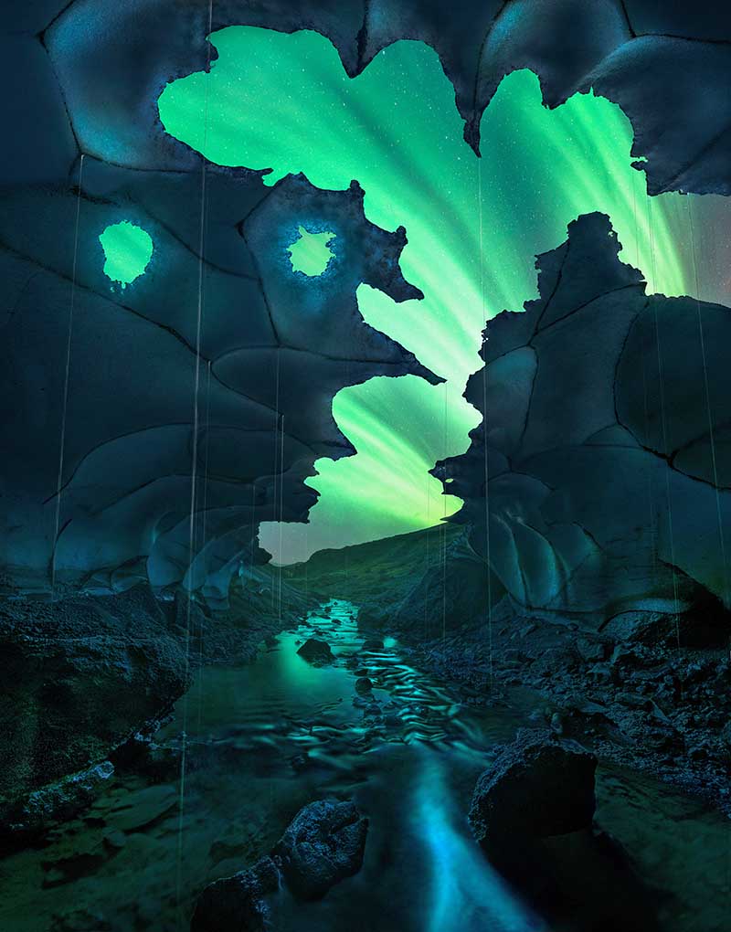 An icecave in laugavegur Iceland, Through the crevices' in the cave the northern lights shine brightly across the sky. The aurora is illuminated in the water on the floor of the cave.