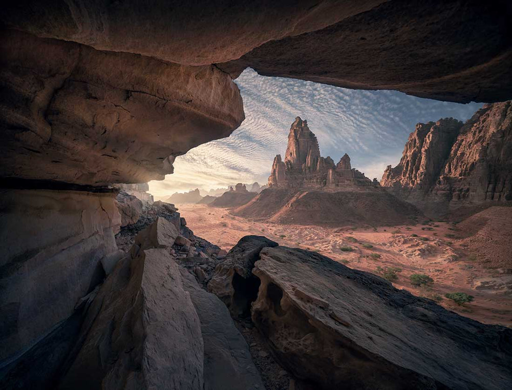 In Saudi Arabia, a large rock is formed in the desert. Seen from a high cave view where rocks point towards the mountain.