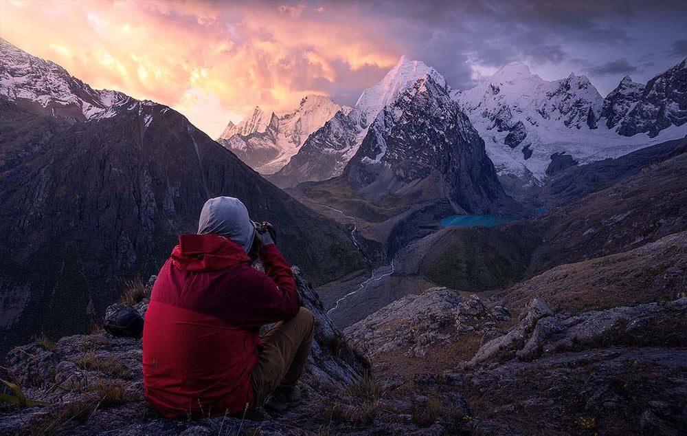 Cordillera Blanca mountains with lakes from high viewpoint. A man takes photo of the sunset and river below the Andes.