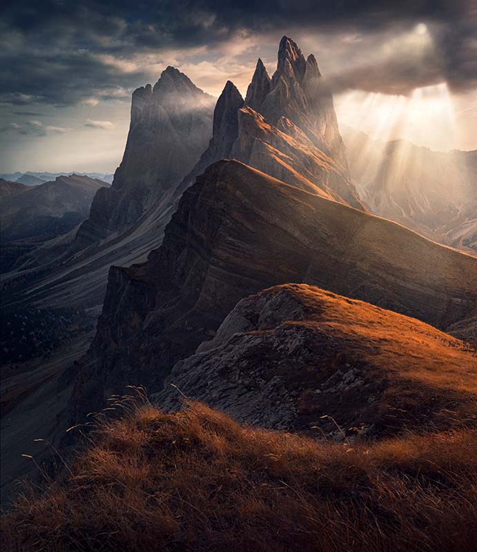 golden sunrise in the dolomites in secede with a grey sky and sunrays.