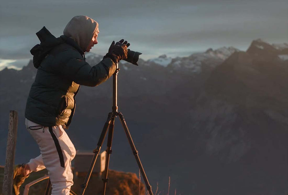 Max Rive on top of a mountain using a tripod and telezoom lens. In the distance are snow capped peaks.