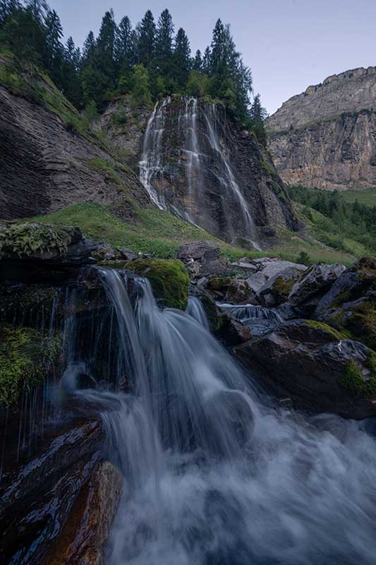 a raw file image of waterfalls in France with too little sky. green trees frame the waterfall.