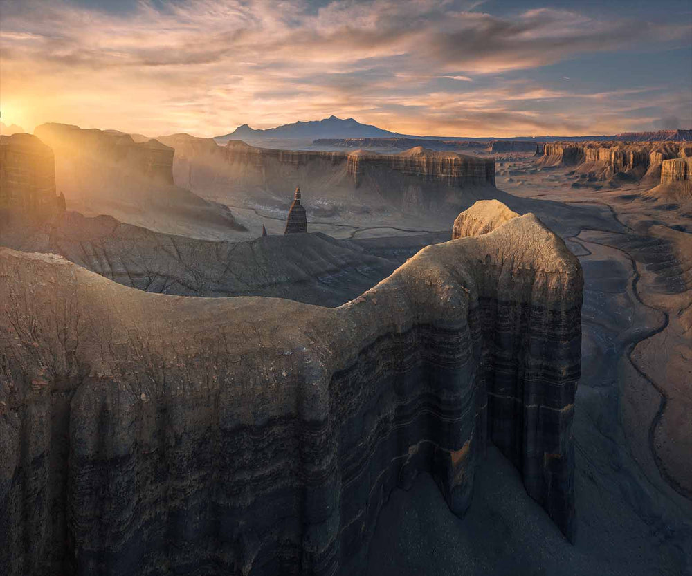 Utah in the southwest USA, the spire of long dong silver at sunset. The light is a yellow golden glow, taken by drone. The layers of sediment in the rock wall frame the spire.