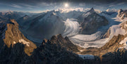 A panorama view above a giant glacier, small person standing on a mountain looking towards the glacier and sun.