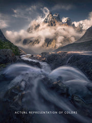 watefall on foreground captured with long exposure - cloudy and dramatic looking mountains in the back