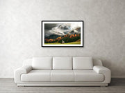 A framed print of the St Johann Church in the Italian dolomites during cloudy weather and autumn colors- hanged on wall