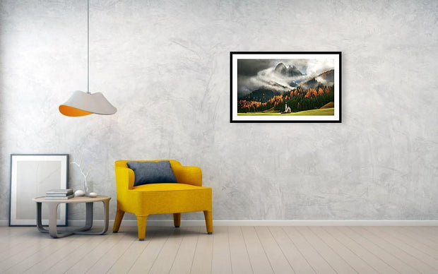 A framed print of the St Johann Church in the Italian dolomites during cloudy weather and autumn colors- hanged in living room
