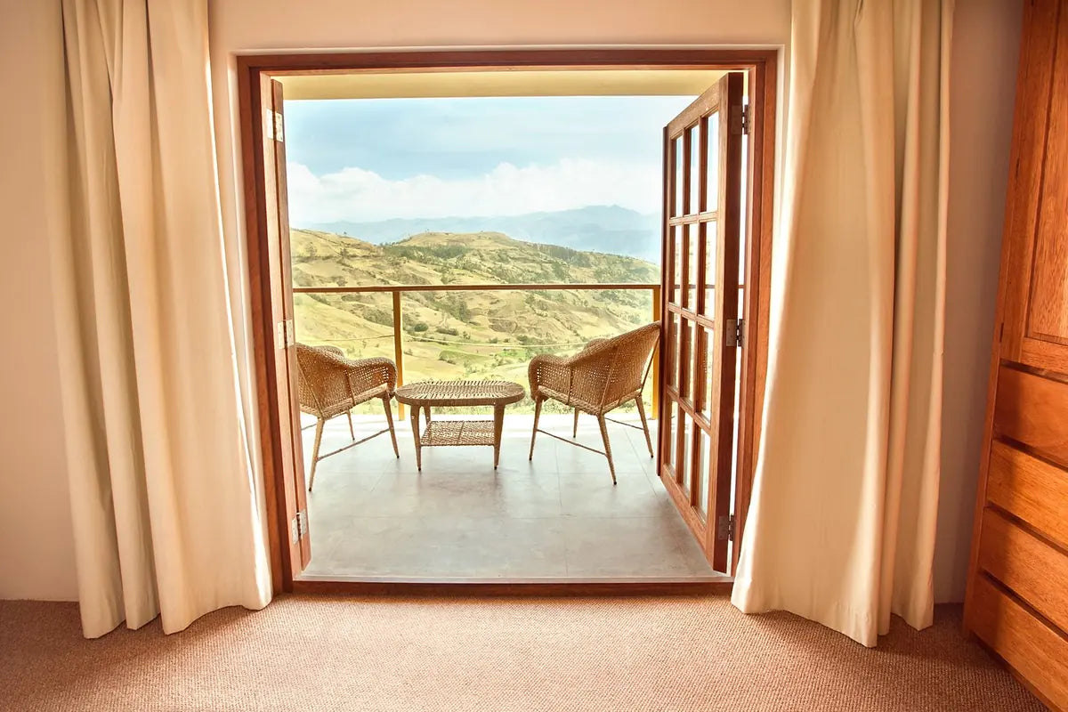 Open balcony doors framing wicker chairs and a view of the mountains at the lodge
