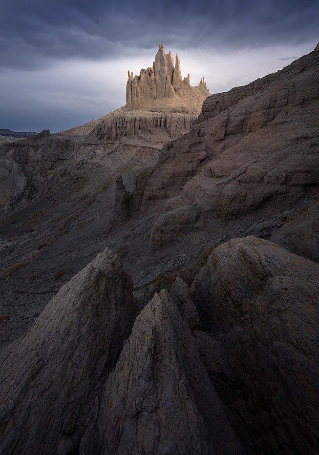 An eroded ridge leading toward a castle-like rock formation beneath dark clouds in Mangystau.