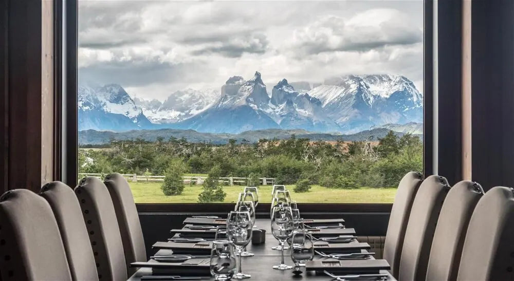 A hotel dining table set beside a large window with mountain views