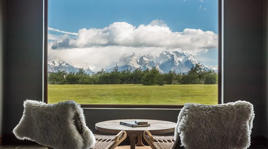 Two lounge chairs beside a picture window overlooking Torres del Paine