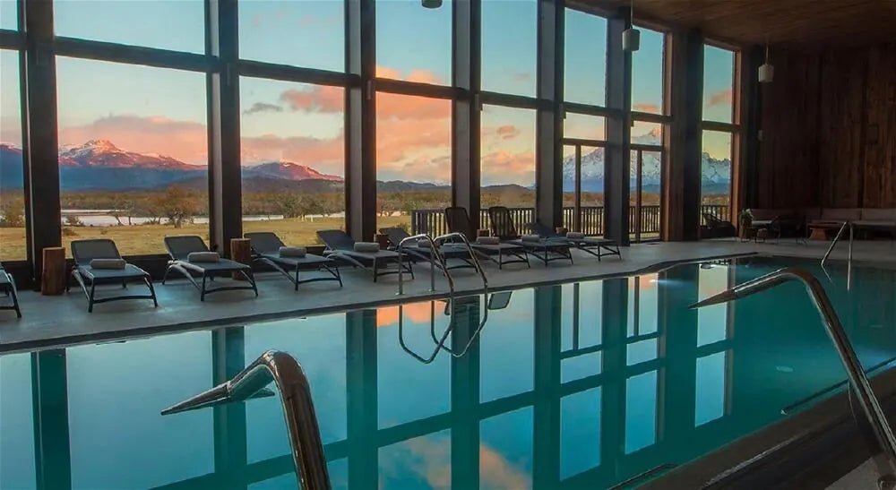 An indoor hotel swimming pool overlooking mountains at sunset