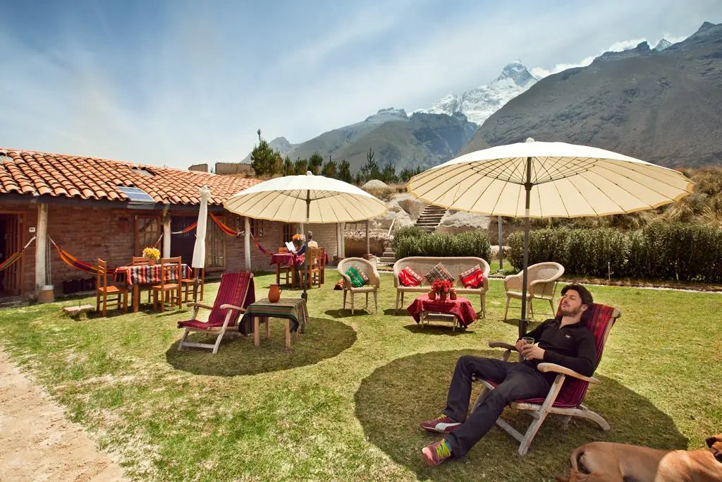 The mountain lodge garden with parasols, chairs and mountain peaks behind