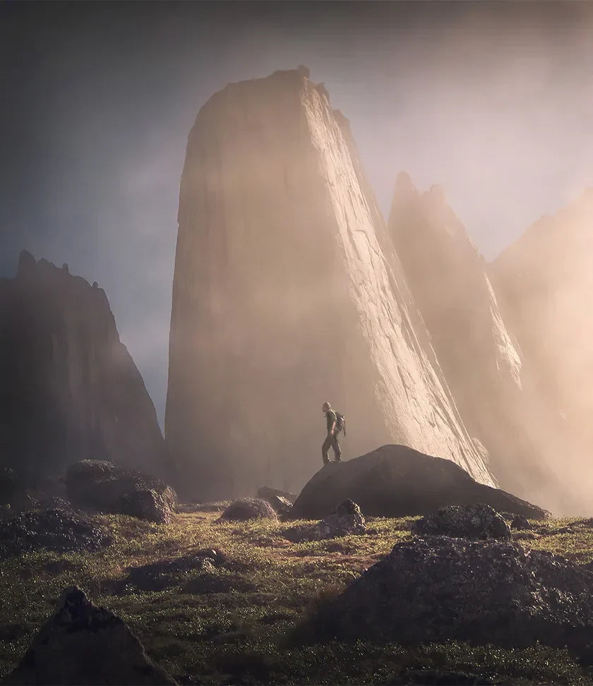 A hiker standing beneath towering mountain walls in warm light