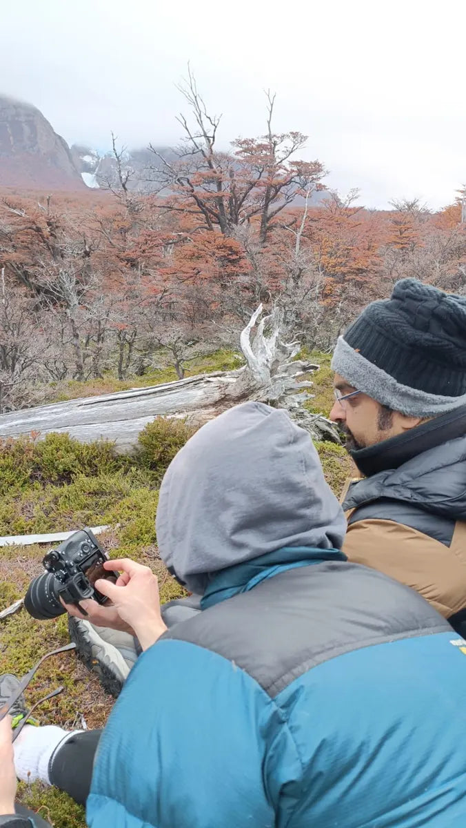 Two photographers looking at a camera among autumn trees in Patagonia
