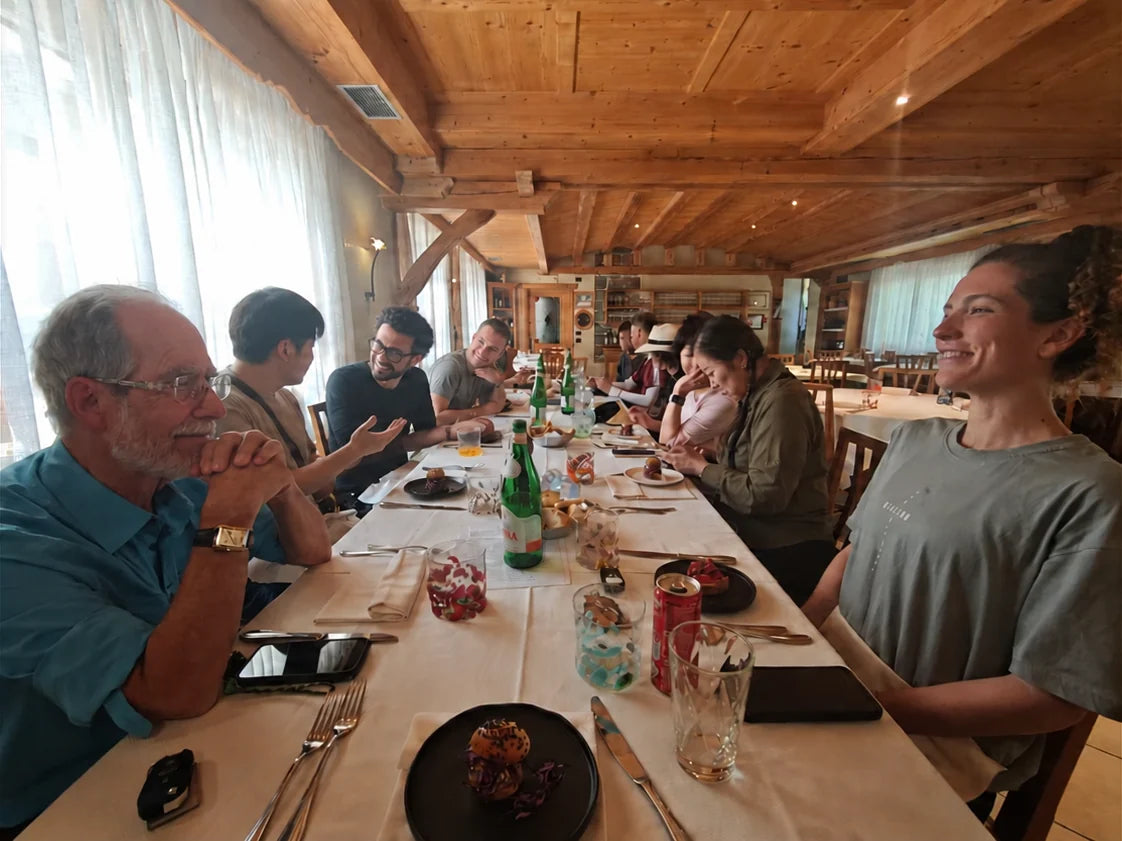 A group sharing dinner and conversation around a long restaurant table