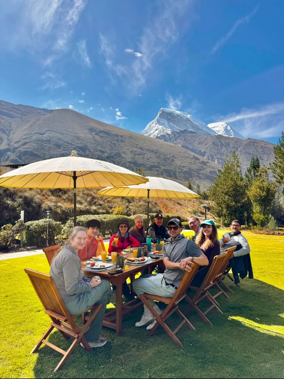 The tour group sharing a meal outdoors beneath mountain peaks