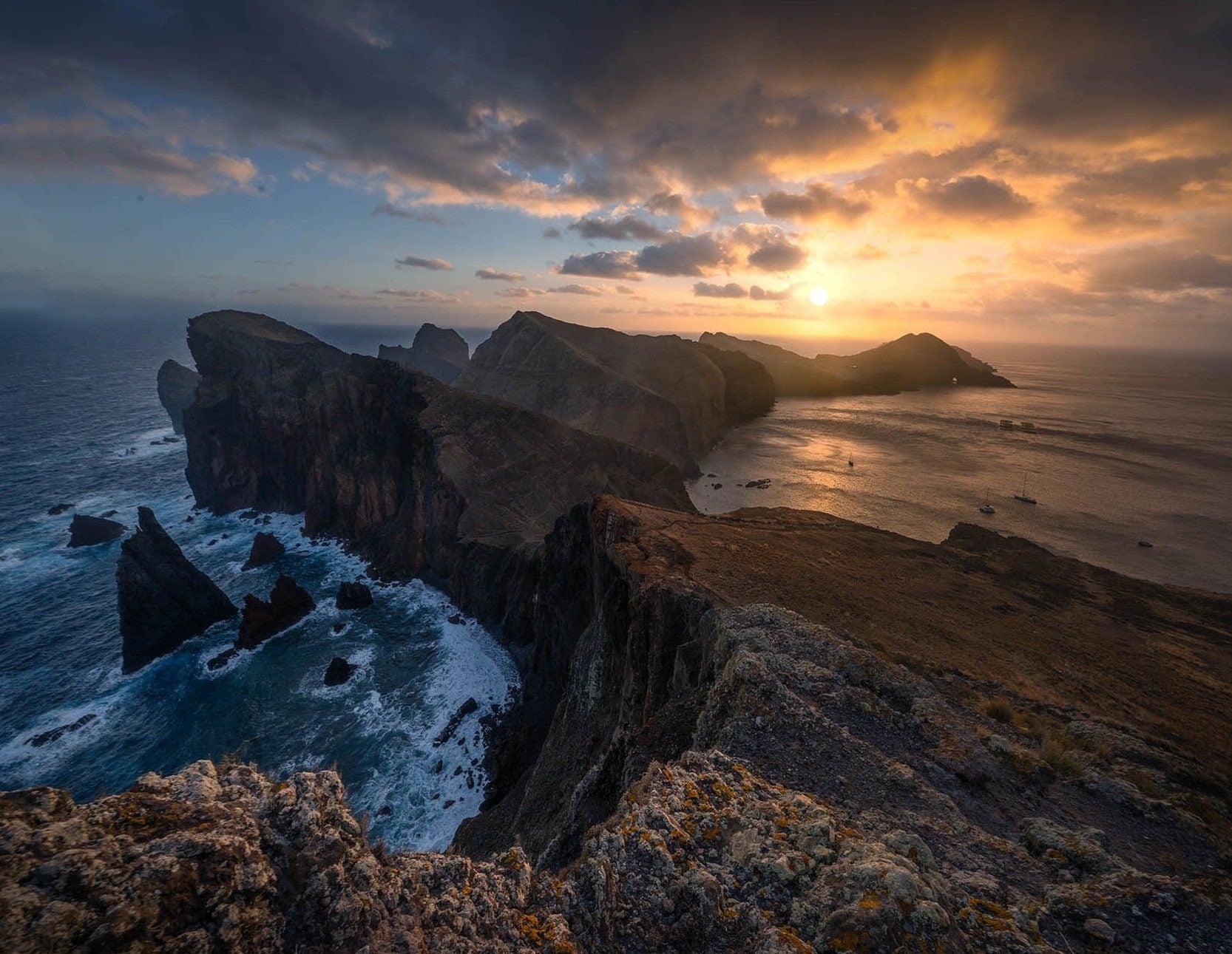 Madeira's rugged coastal headland surrounded by the Atlantic beneath a golden sky.