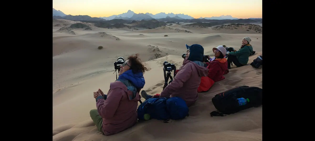 A photography tour group sitting together on Saudi Arabian dunes at sunset